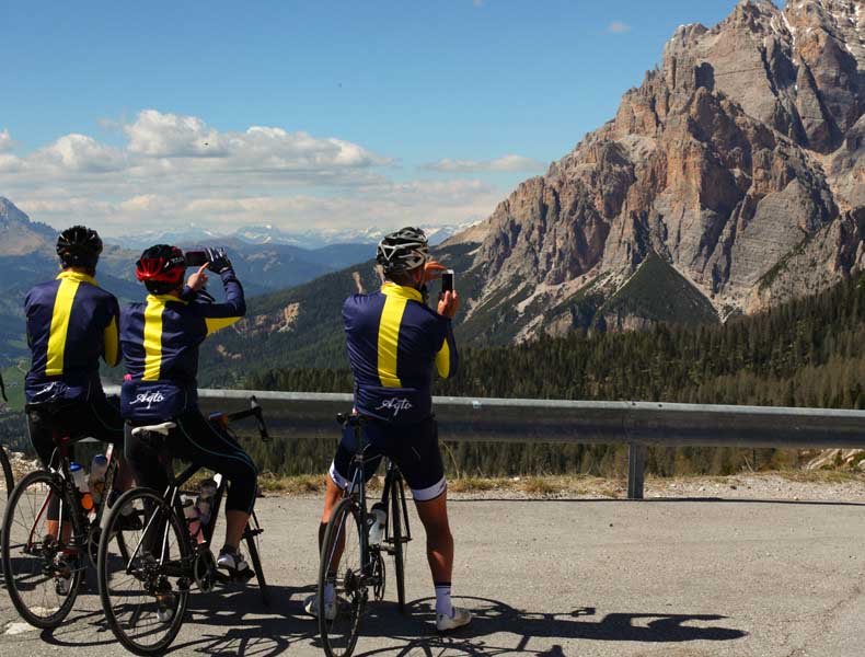 Three cyclists taking photographs of the Dolomite mountains