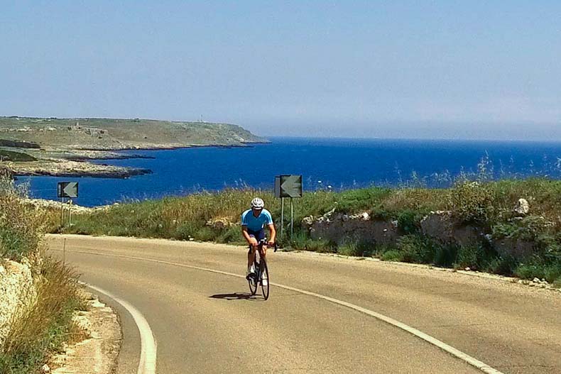 A cyclist riding in Puglia along the coastline