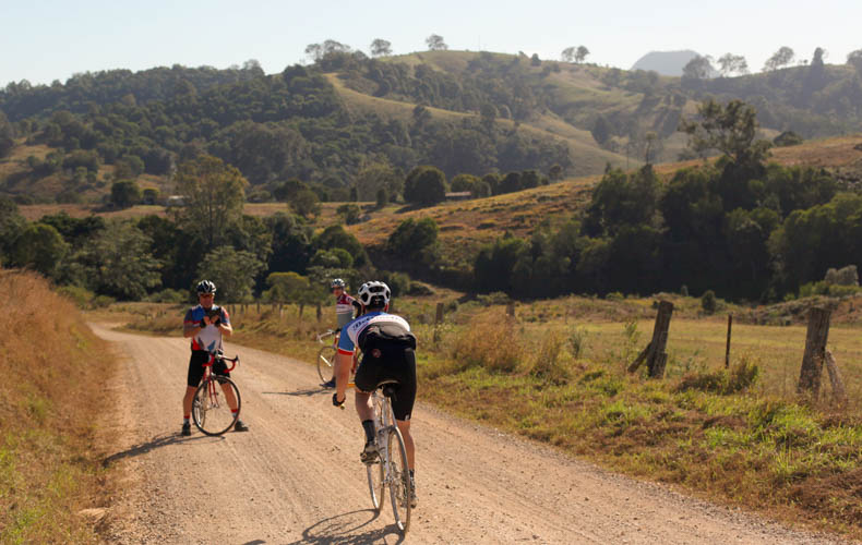 A riders cycling on steel bikes on a gravel road near Noosa