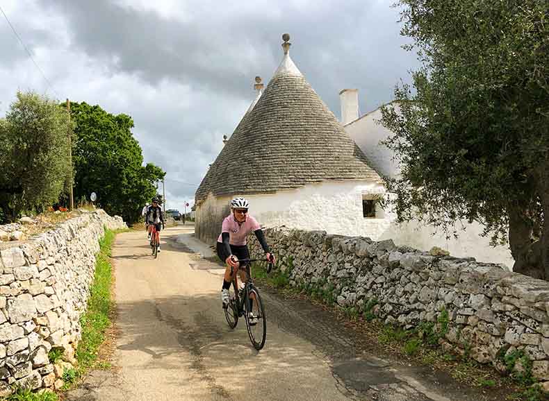 A lady cycling past a trulli in Puglia