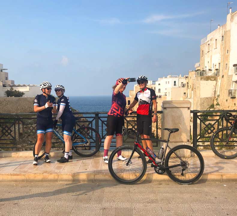 Cyclists taking photos on the bridge at Polignano a Mare