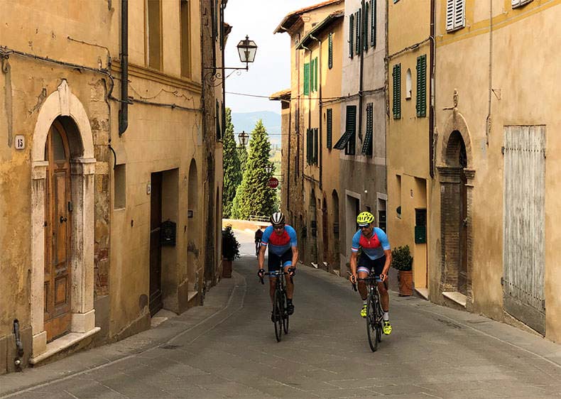 Two cyclist riding through a Tuscan town
