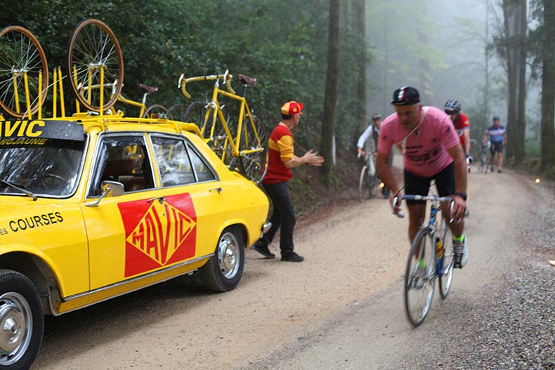 cyclists riding past the MAvic team car during L'Eroica
