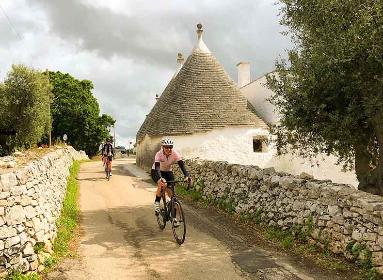 A woman cycling past a trulli in Puglia