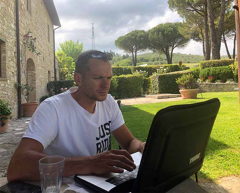 a man working on a computer in a Tuscan garden