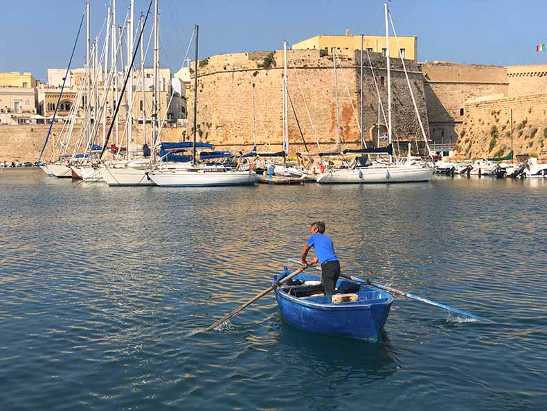 a fisherman rowing a small boat in Gallipoli, Puglia