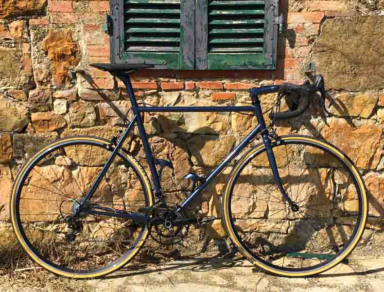 a handmade italian bicycle leaning against a stone wall