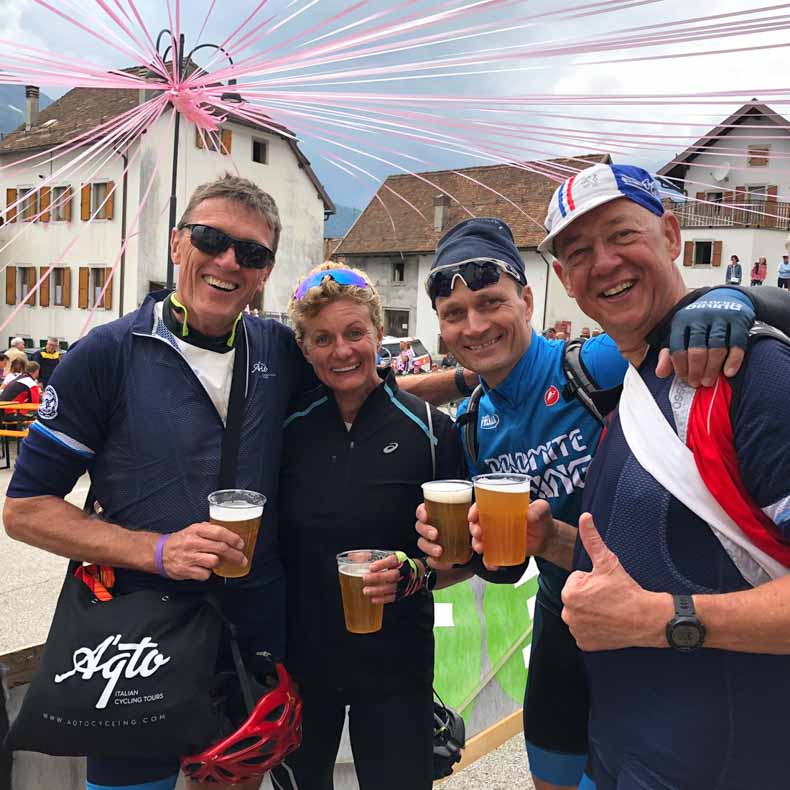 Four riders drinking beer as they wait for the Giro cycling race to pass
