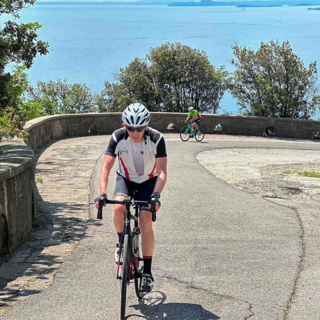 A man cycling up a hill beside Lake Garda