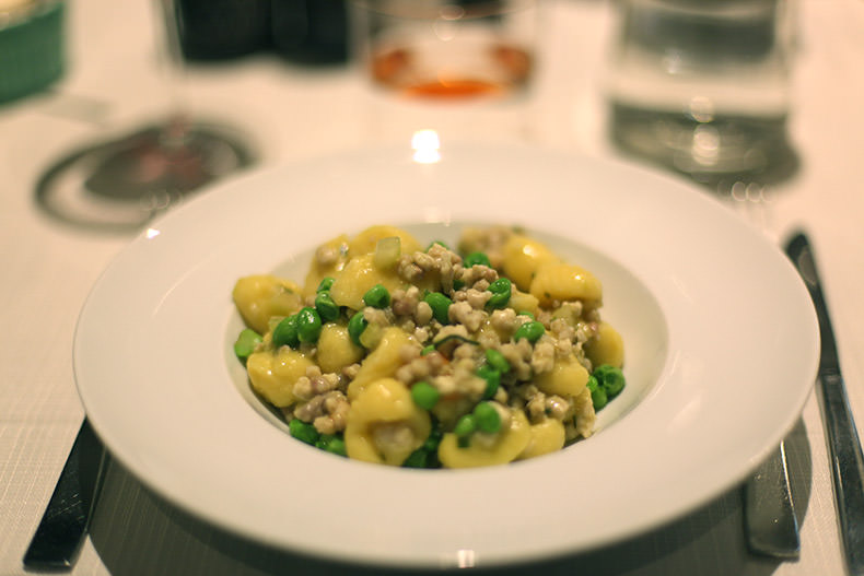 a bowl of gnocchi with rabbit and peas