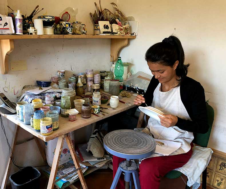 a lady hand painting ceramics in Tuscany