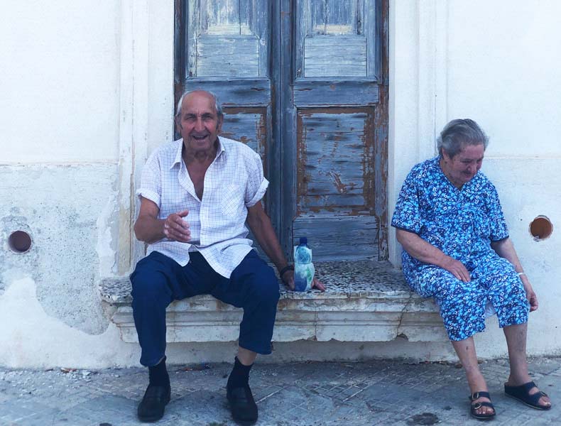Two people sitting on a step in an old town in Puglia