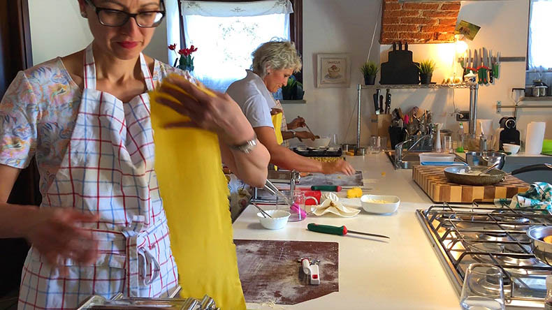 A woman rolling out pasta during a cooking class in Piemonte