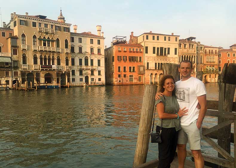 Two people standing at the edge of the Grand Canal in Venice