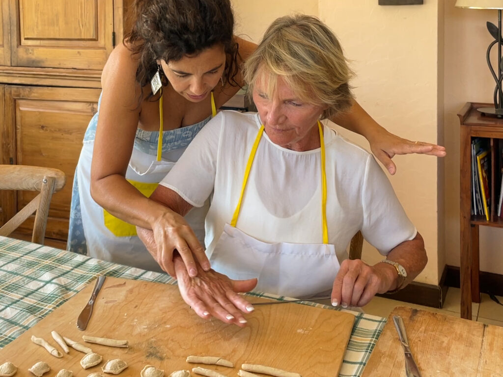 A lady being shown how to make orecchiette in Puglia Italy