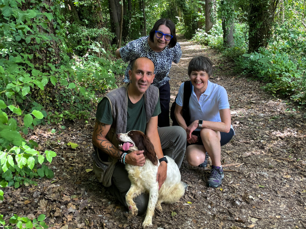 Two women in the forrest with a truffle hunter and his dog.