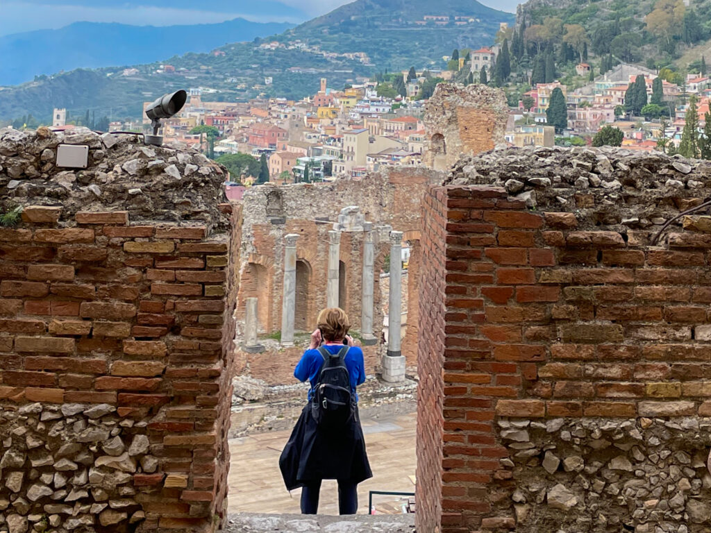 A woman photographing the ancient theatre in Taormina, Sicily