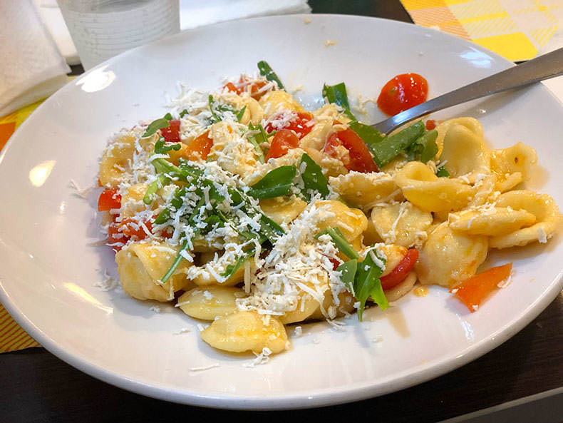 a plate of orecchiette with basil and tomato