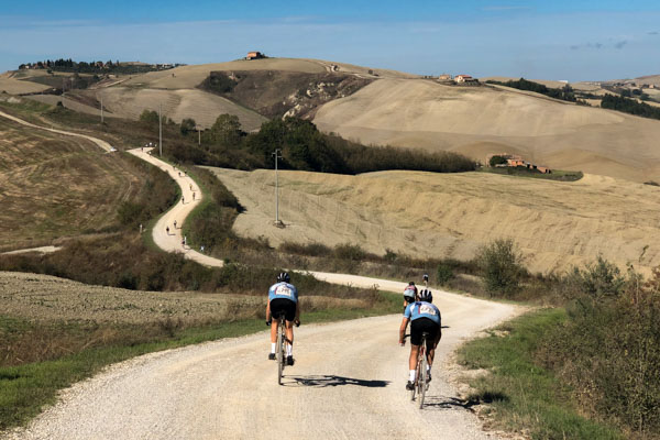 a few riders cycling along the gravel roads of Tuscany