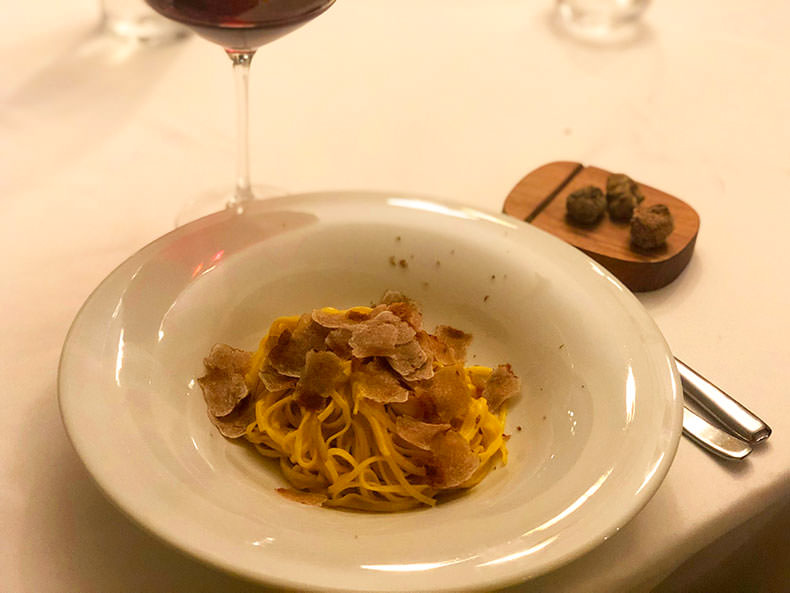 a plate of pasta with truffles and a glass of Barolo