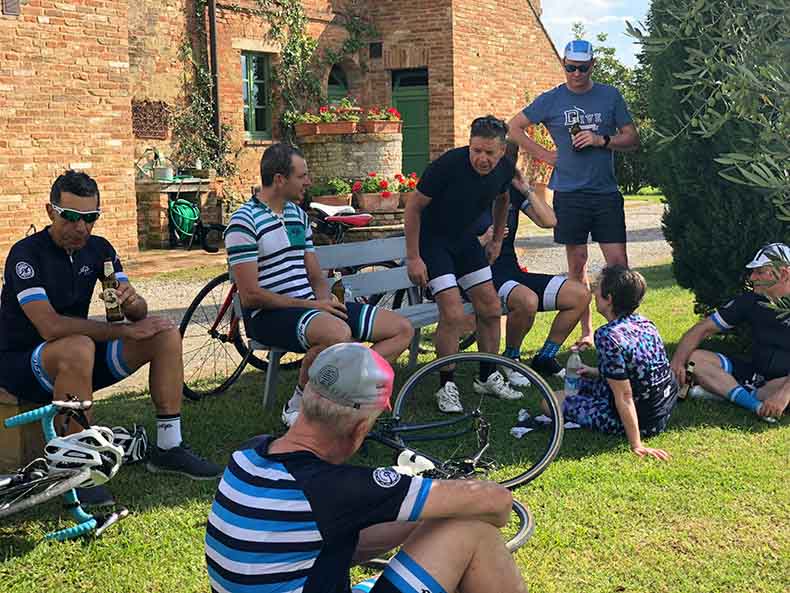 cyclist having a refreshing post ride beer sitting on the grass in Tuscany