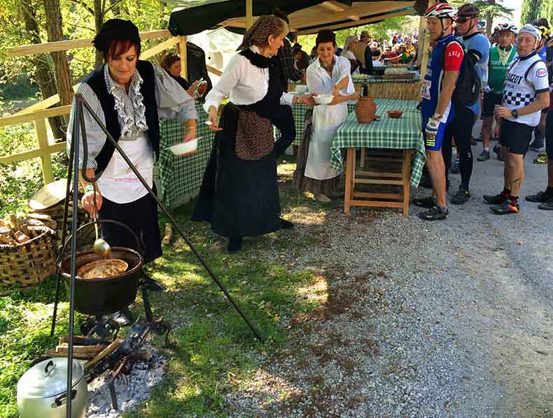 A lady stirring a pot of soup at a L'eroica rest stop