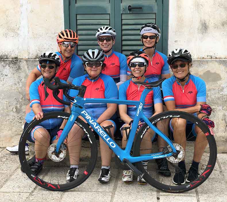 some women cyclists sitting on a step with a Pinarello bicycle