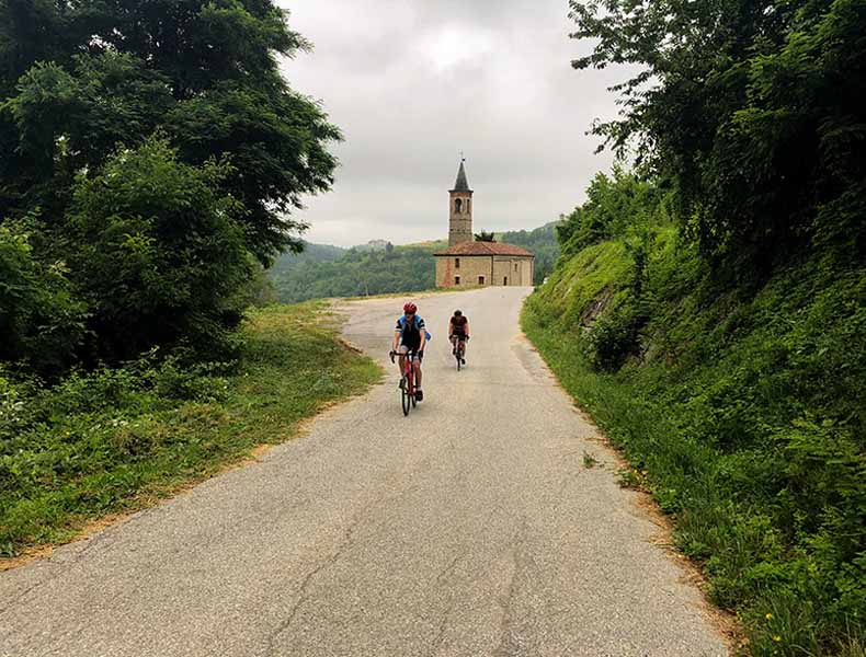 Two cyclists riding past a church in Piemonte