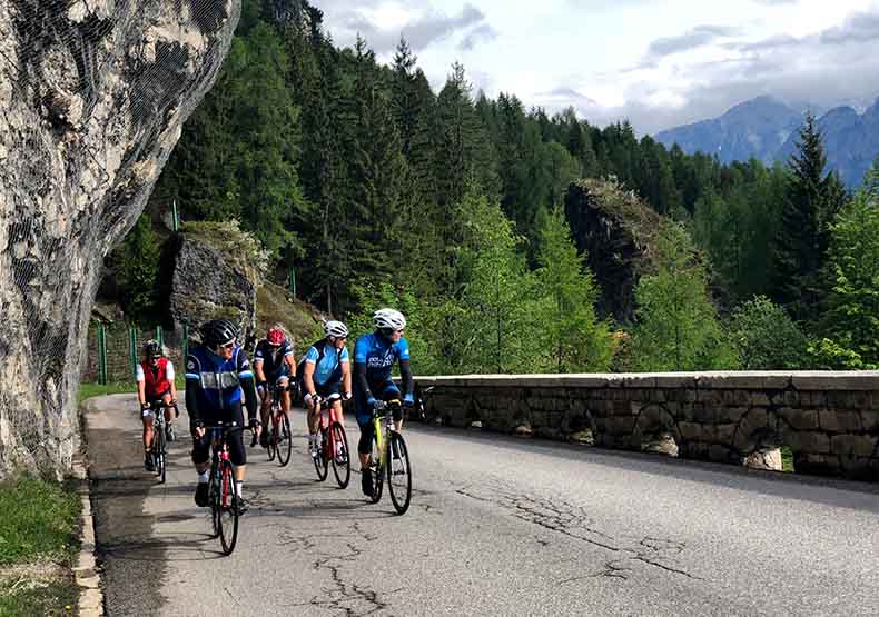 Cyclists looking at the view of the Dolomites as they climb up a hill