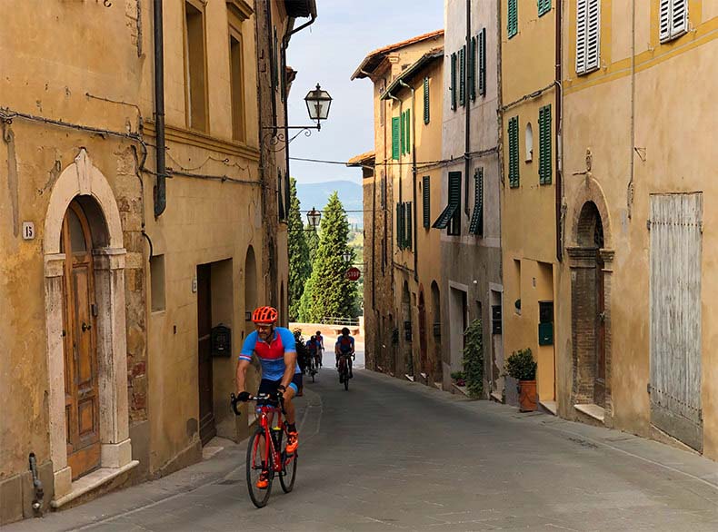 A man cycling through a Tuscan town on a cycling Holiday