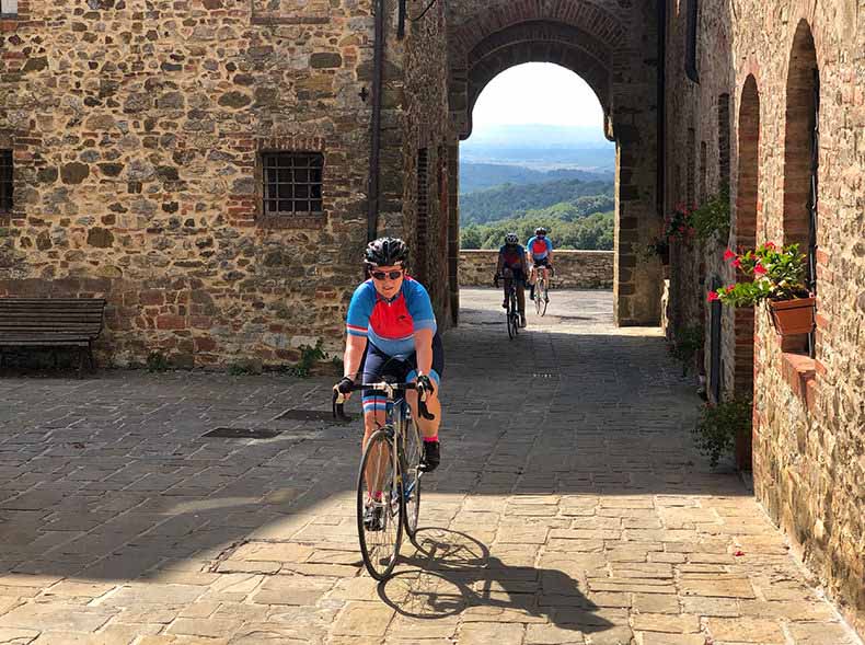A cyclist riding through an old stone hamlet in Tuscany