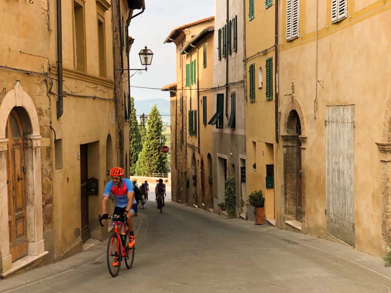 A man riding through a town in the Val d"orcia of Tuscany