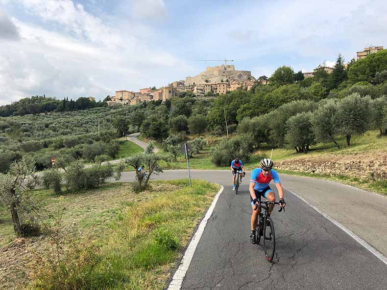 Two cyclists riding through an olive grove in Tuscany