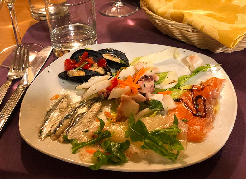 A glass of wine and a plate of mixed seafood antipasto