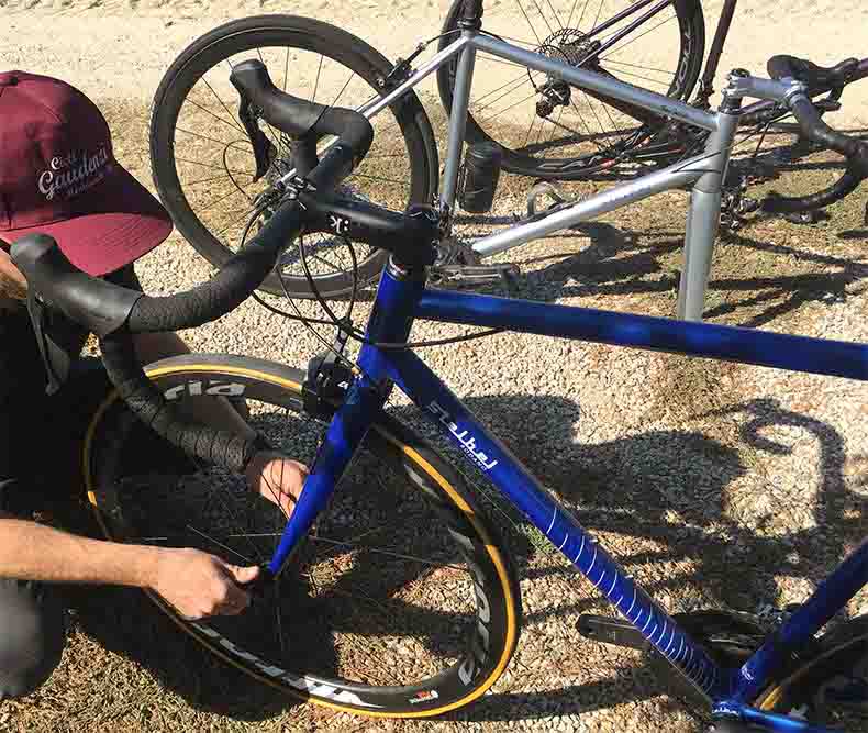 a man putting the wheel onto a bicycle