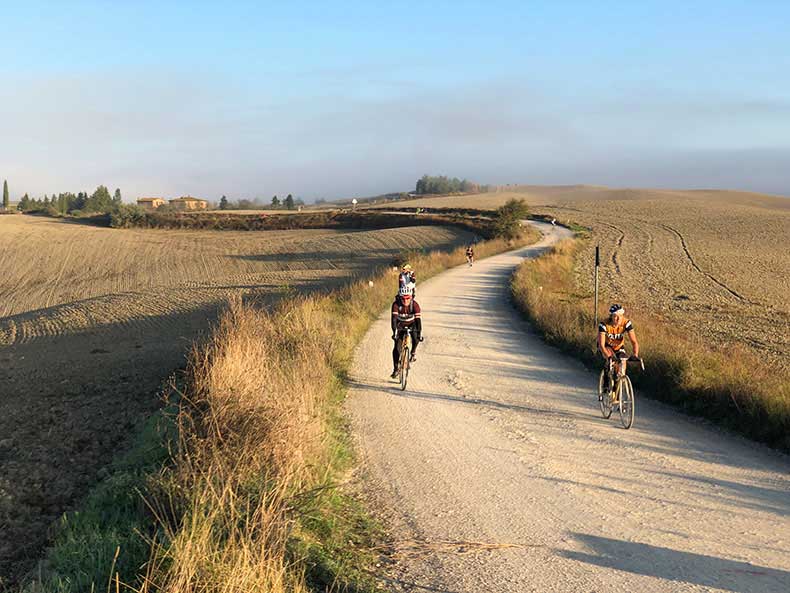 two cyclist riding along the gravel roads of Tuscany during L'eroica