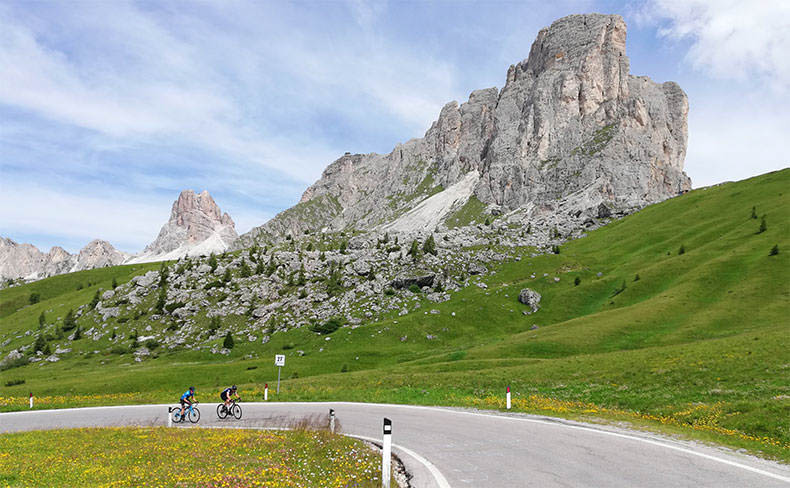 two riders cycling past Passo Giau