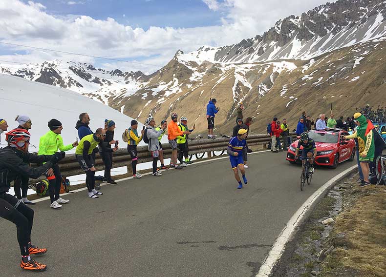 A fan running alongside a bike racer at the Giro d'Italia on Passo Stelvio