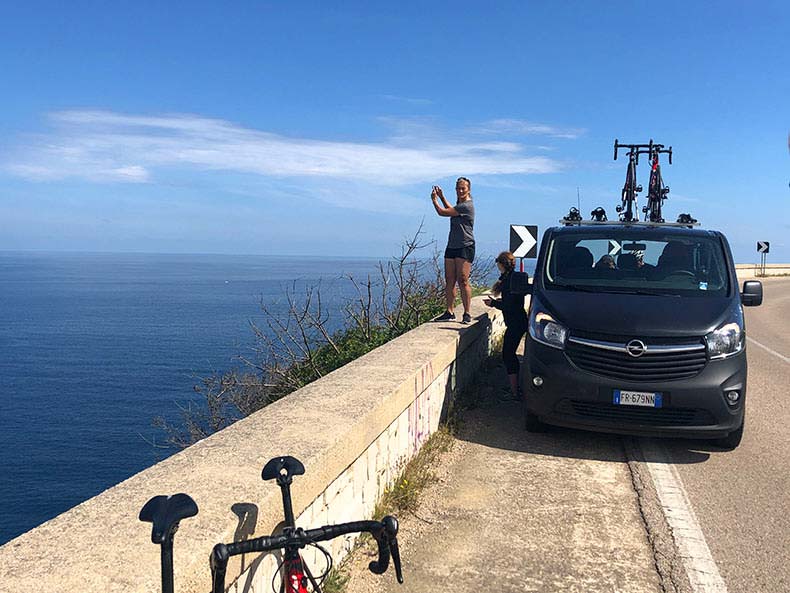 A lady taking a photo off the ocean beside the tour support van