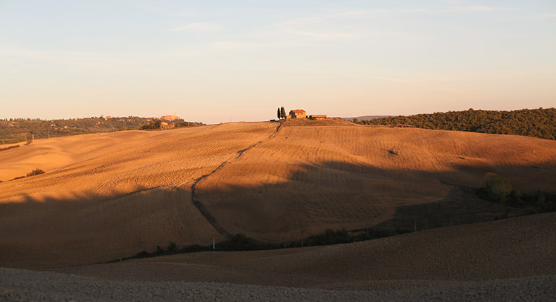 A stone house on a hill bathed in sunset in Tuscany