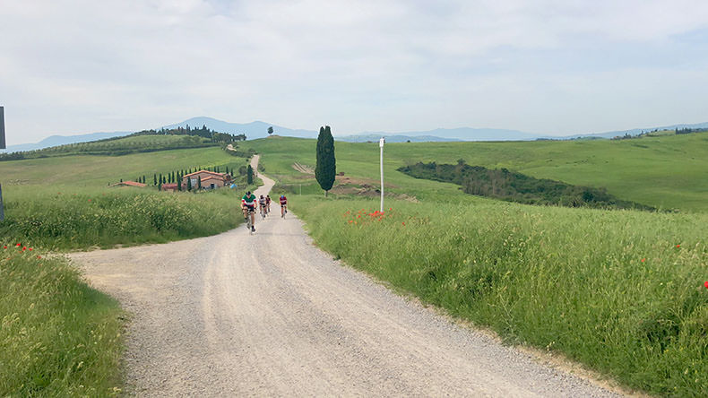 The beautiful Tuscan landscape with cyclists riding steel bikes during L'Eroica