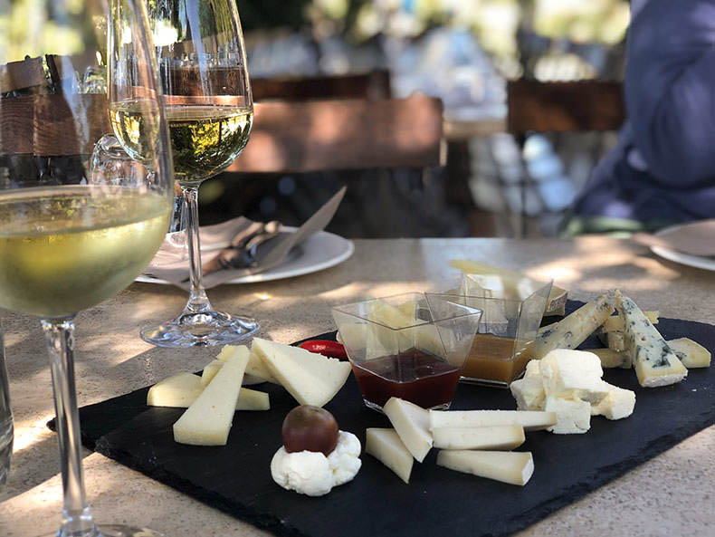 A plate of pecorino cheese and glasses of white wine