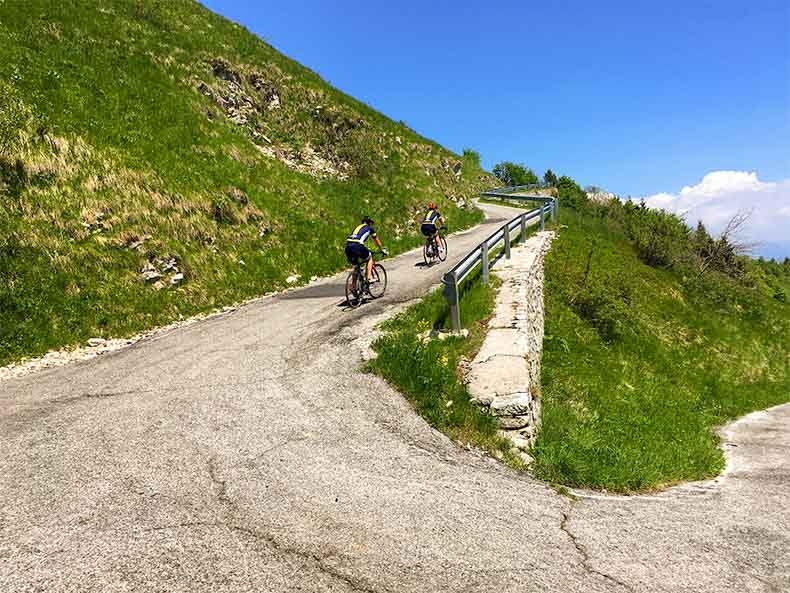 Two cyclists ridng up the steep slopes of Monte Grappa