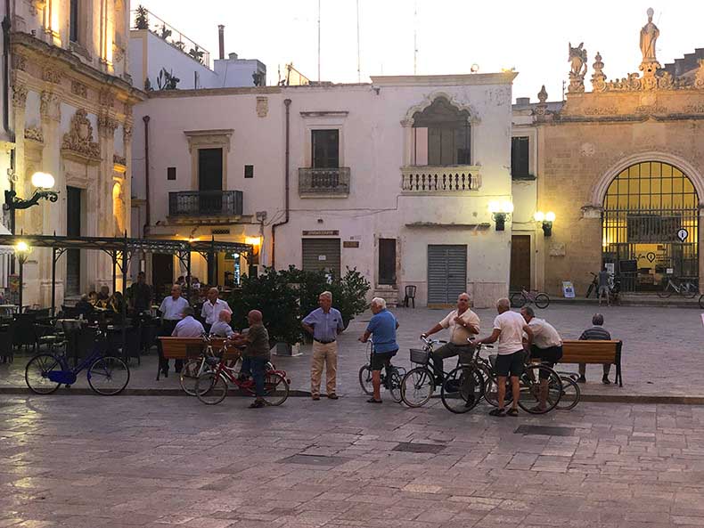 A group of men on bicycles ina small Italian town at dusk