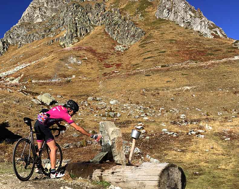 a cycling filling their water bottle from a mountain tap