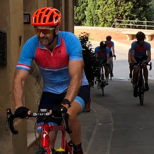 A man riding a bike through a small Tuscan town