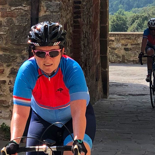 A woman riding a bike through a small Tuscan hamlet while on a cycling holiday in Italy