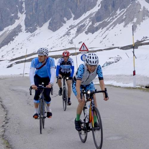 A group of riders cycling to the top of Passo Giau in the snow