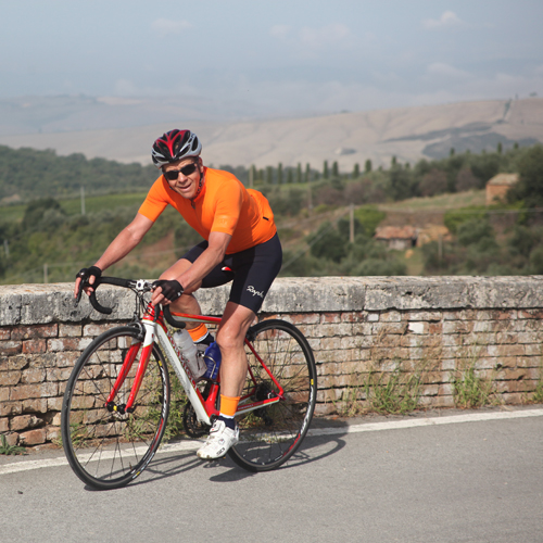 A man riding a bicycles across a bridge in Tuscany