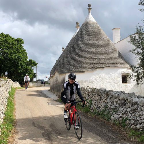 A lady riding past a trullii in Puglia